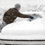 windscreen replacement services - Young man brushing the snow off his car